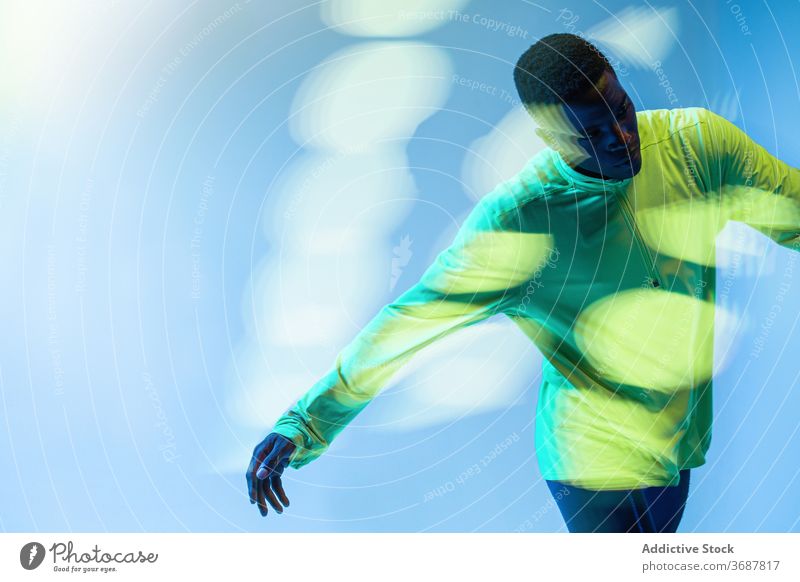 Athlete running in studio sportsman runner athlete muscular determine confident active physical neon young black african american ethnic male training workout