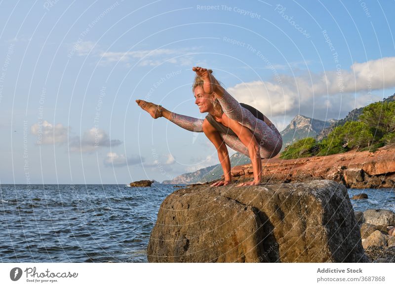 Woman doing yoga exercises on the rock facing the sea future mountains nature strong pose oriental health concentration sun sunrise harmony strength variation