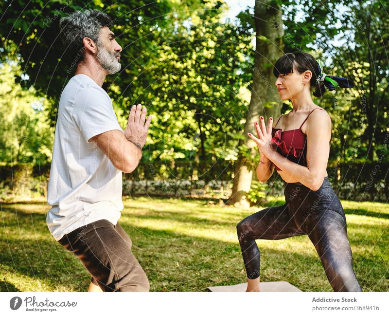 Man and woman practicing balance yoga pose in park couple asana goddess utkata konasana practice together stand wellness lifestyle harmony energy vitality