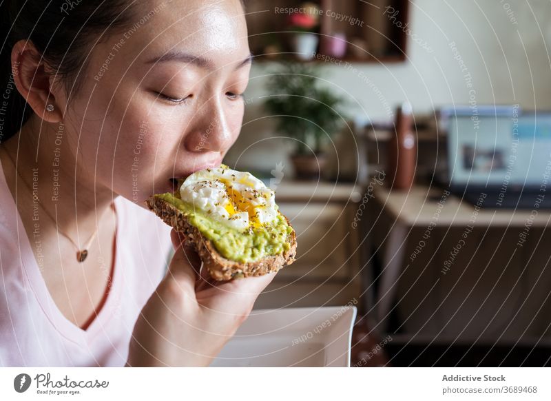 Ethnic woman eating breakfast on bed toast avocado egg delicious healthy nutrition morning female ethnic asian cozy home food relax comfort tasty meal fresh