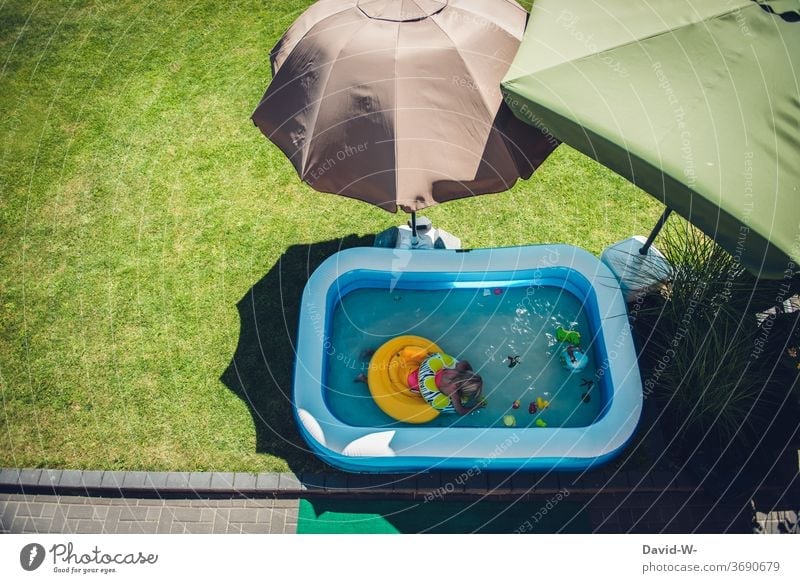 Child bathes in the garden in a paddling pool surrounded by parasols that provide shade Paddling pool Sunshade shade dispenser sunny Quarantine Home Infancy