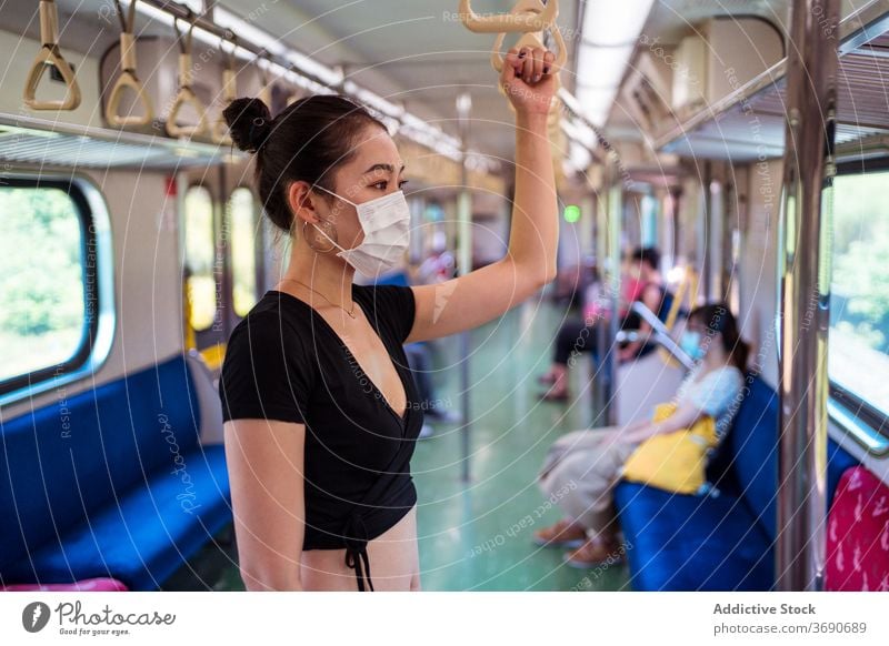 Asian woman in mask in train travel coronavirus public transport outbreak protect commute female ethnic asian modern passenger stand trip journey safety covid