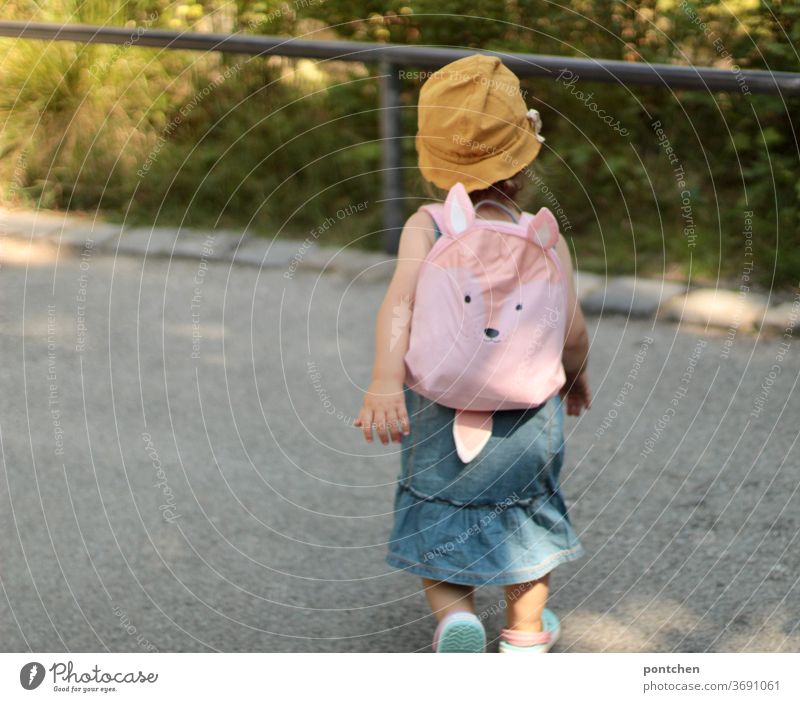 A toddler with a yellow sun hat and a cute backpack in pink. Family outing, family holiday Toddler Backpack Trip urlsub voyage garments Summer Self-confident