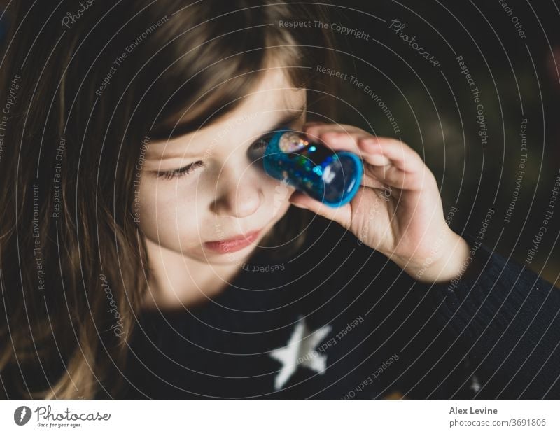 Child looking through a toy kaleidoscope child girl playing young playful science learning
