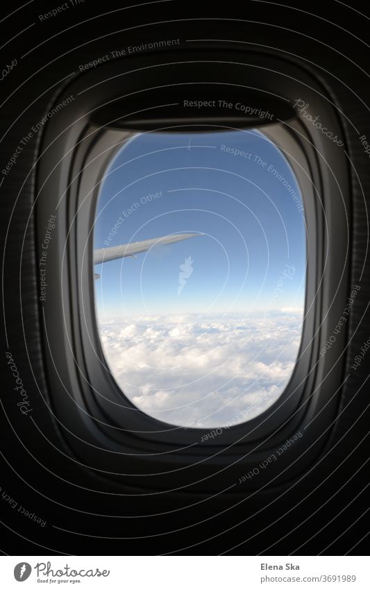 Round window of an airplane with the view on the sky, clouds and wing Airplane window Aircraft travel tourism armosphere