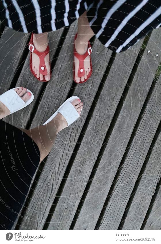 Feet on the bar from above foot Footwear bathing shoes Sandals Legs wood wooden walkway Woman 2 High heels feminine Exterior shot Striped Pants Red White Gray