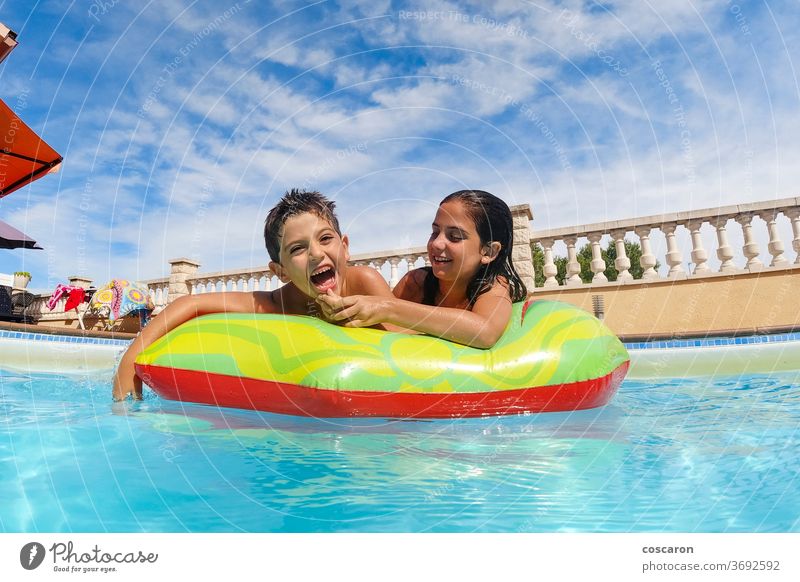Two funny kids  in the pool on an air mattress activity blue carefree child childhood children cute enjoy family float freshness friend friends friendship girl