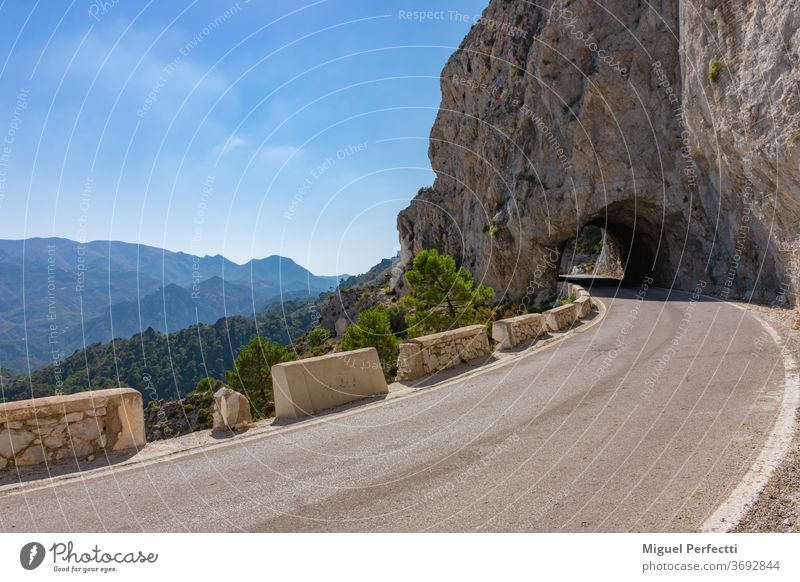 Narrow high mountain road with a tunnel made of stone and views of other peaks, is known as Carretera de la Cabra, Granada, Spain. landscape nature rock travel