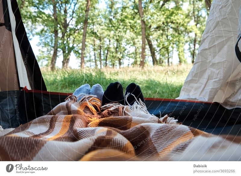 Two people lie in a tourist tent, inside view. Feet under the covers in tent. Tourist camp forest background tourism nature wild grass sun trip tree activity