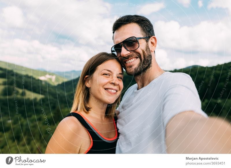 Young couple taking a selfie in the mountains adult adventure beautiful camera caucasian faces female freedom friends happy hike hiking journey landscape