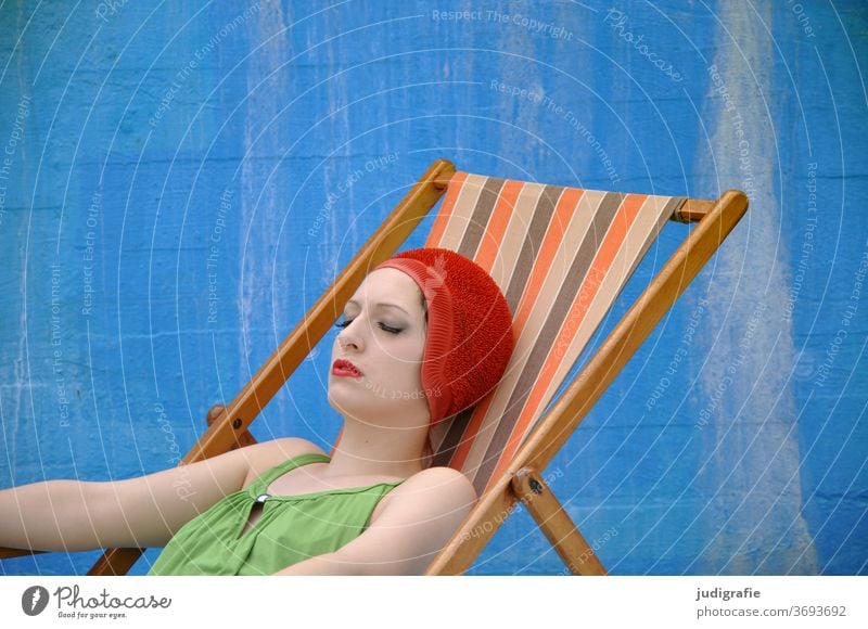 The girl with the beautiful red bathing cap and green swimsuit takes a sunbath in a deck chair. A summer love. Woman Swimwear Bathing cap Swimsuit Summer Skin