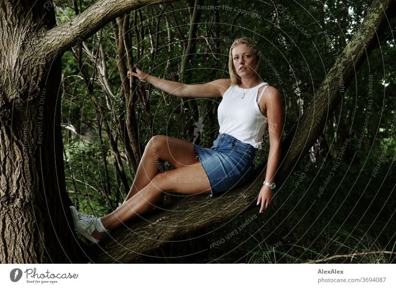 Portrait of a young woman sitting on a branch Young woman Woman Blonde smile portrait Jewellery already Long-haired Landscape tanned Self-confident Summer