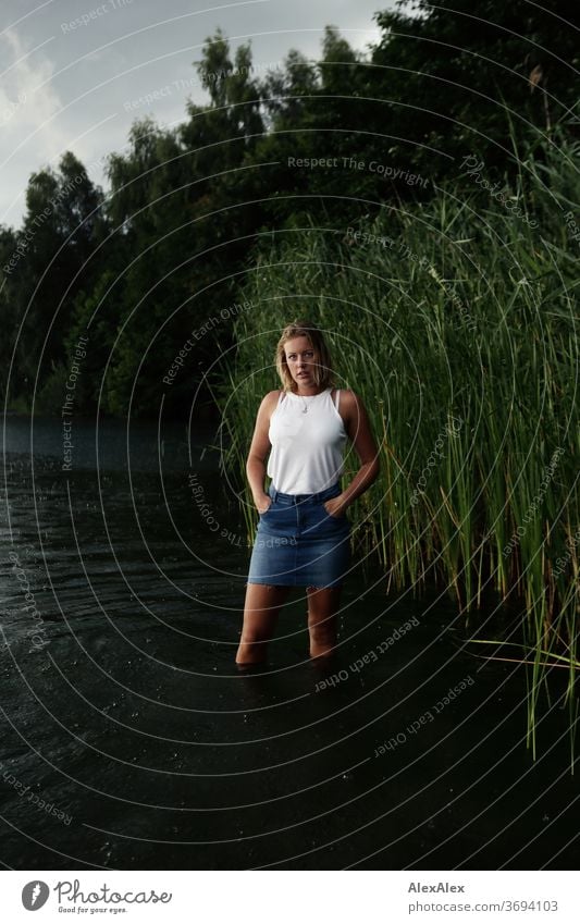 Portrait of a young woman in a lake in front of reeds Young woman Woman Blonde smile portrait Jewellery already Long-haired Landscape tanned Self-confident