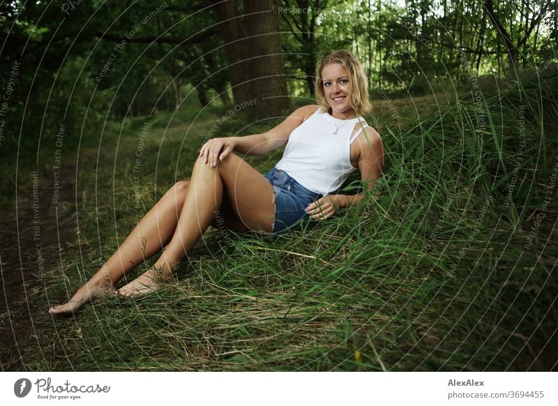 Portrait of a young woman sitting in nature and smiling Young woman Woman Blonde smile portrait Jewellery already Long-haired Landscape tanned Self-confident
