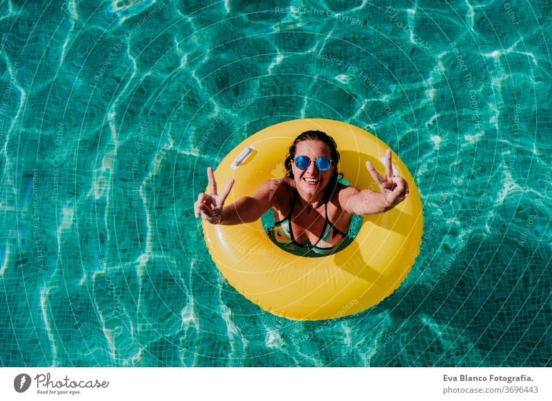 top view of happy young woman floating in a pool in a yellow donuts. summer and fun lifestyle inflatable swimming bubbles caucasian dive clear health light