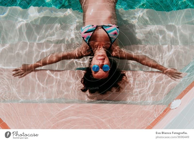 top view of happy young woman floating in a pool. summer and fun lifestyle underwater swimming bubbles caucasian dive clear health light action wet swimmer blue