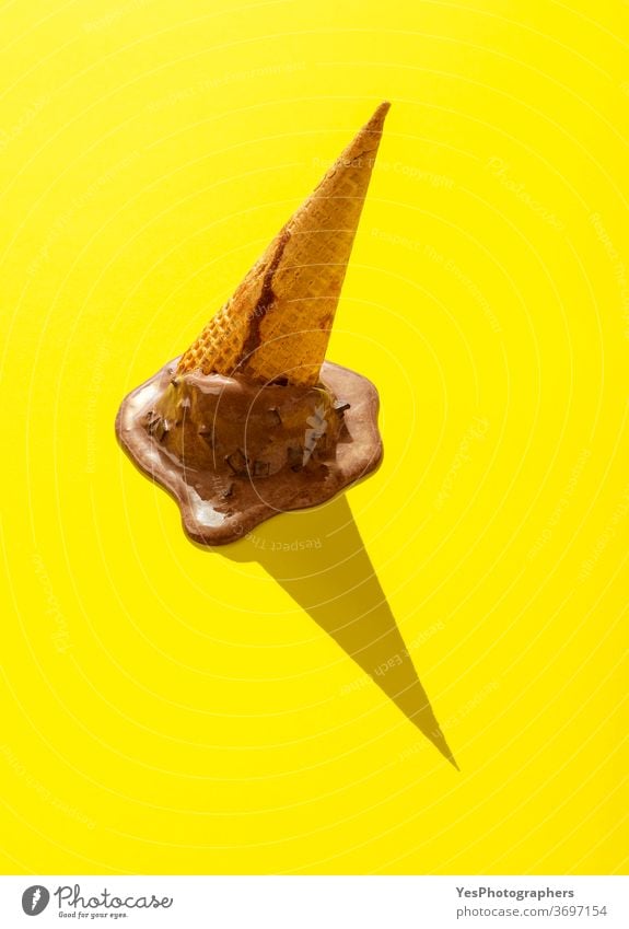 Cone ice cream melting on a yellow table. Chocolate ice cream upside down in bright light accident background brown childhood choco chocolate concept cone