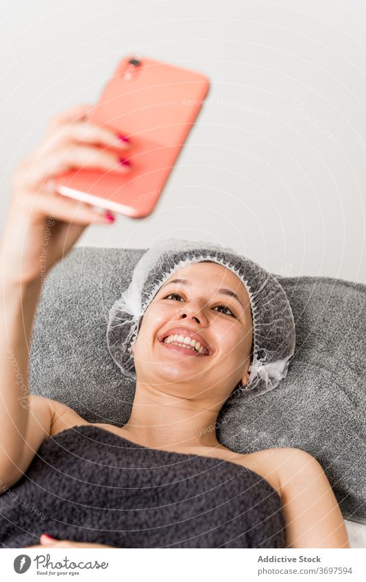 Happy woman taking selfie after beauty treatment cosmetology happy smartphone satisfied client facial skin care young female photo enjoy mobile salon spa