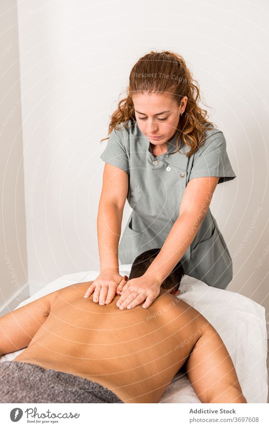 Masseuse massaging back of male patient massage treat professional masseuse procedure care therapy press wellness client salon work wellbeing occupation job
