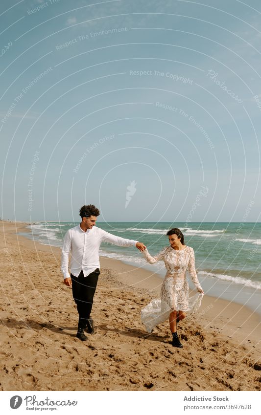 Newly married couple walking on sandy beach