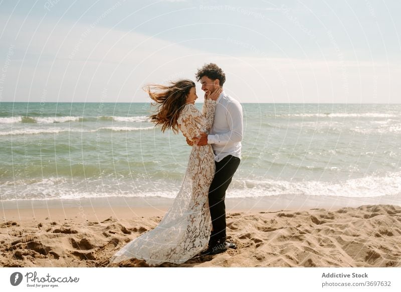 Happy newlywed couple standing against waving sea beach romantic happy cheerful together embrace relationship love nature sand gentle seaside harmony amorous