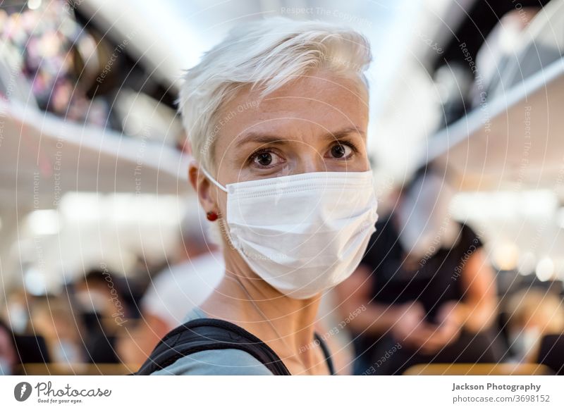 Woman standing in the airplane wearing face mask woman travel traveller aisle corridor interior lifestyle post-covid-19 facemask corona virus safe new normal