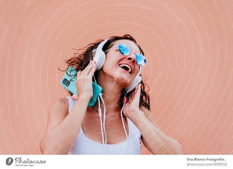 young happy woman outdoors listening to music on headset and mobile phone. Lifestyle at the city. Summertime. close up view music headset urban sunglasses