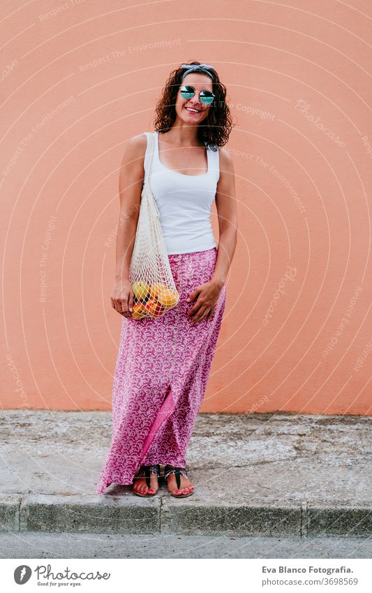 woman walking by the city, holding a cotton bag with fruit. Eco friendly, zero waste concept caucasian urban consumer green environment buy money pursed reduce