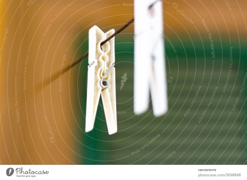 a white plastic clothespin hanging. rope laundry blue clip line string background clamp peg green object clothesline household housework closeup isolated home
