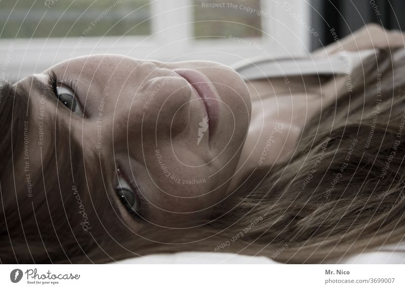Young woman lies on her back in bed and looks smiling into the camera Lie Face Eyes Hair and hairstyles Nose Looking portrait Lips Mouth Skin Head Freckles