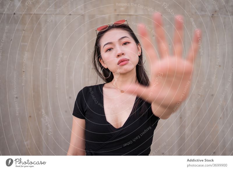 Ethnic woman showing stop gesture in street sign refuse demonstrate symbol urban style female ethnic asian city daytime defense gesticulate confident serious