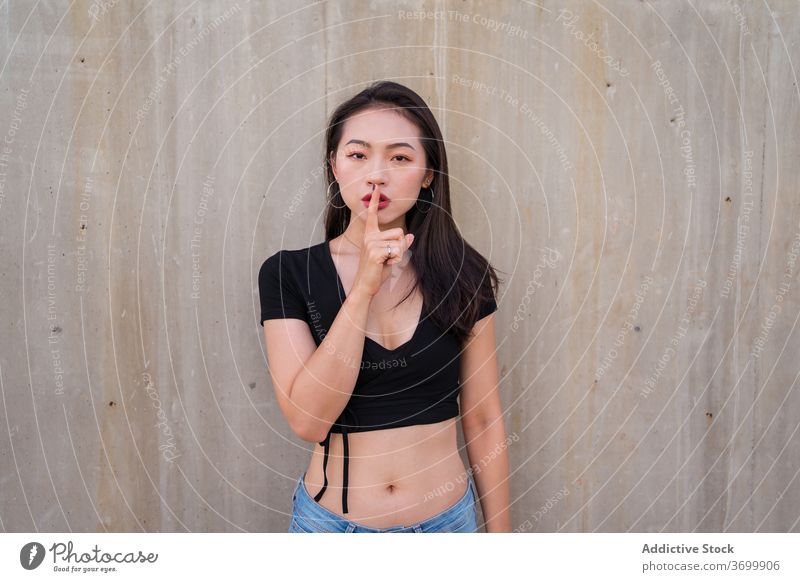 Ethnic woman showing silence gesture silent sign hush index finger gesticulate calm shh secret female ethnic asian quiet charming demonstrate stand peace symbol