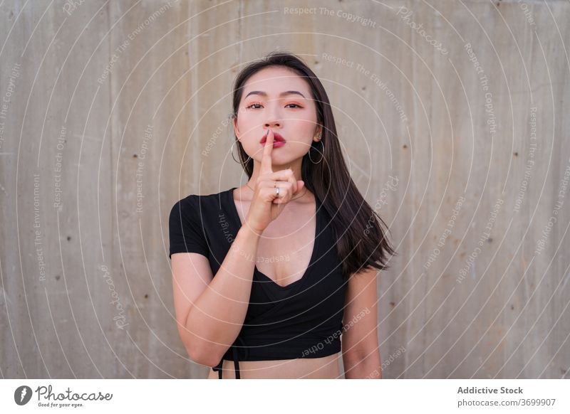 Ethnic woman showing silence gesture silent sign hush index finger gesticulate calm shh secret female ethnic asian quiet charming demonstrate stand peace symbol