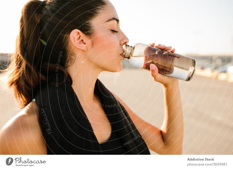 Young athletic woman with bottle of drink on street sporty rest fit eyes closed positive active training stand refreshment energy young female beverage relax