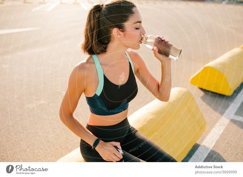 Young athletic woman with bottle of drink on street sporty rest fit eyes closed positive active training refreshment energy young female beverage relax