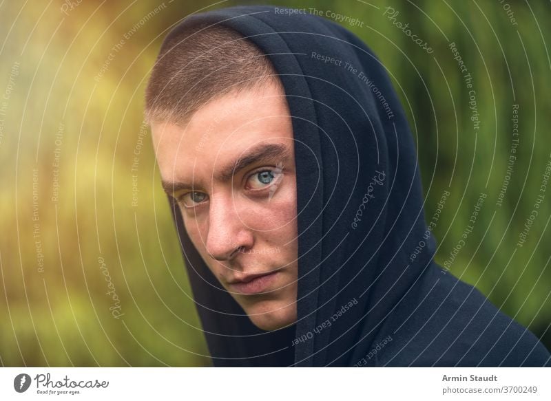 Portrait of a serious young man in a black hoodie portrait look teenager looking male beautiful casual caucasian outdoor confident model lifestyle sunlight