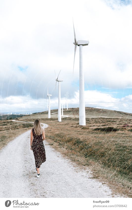 Woman walking by a wind turbine farm woman person young eco energy electricity ecology copy space sky galicia spain clean turbines alternative generator
