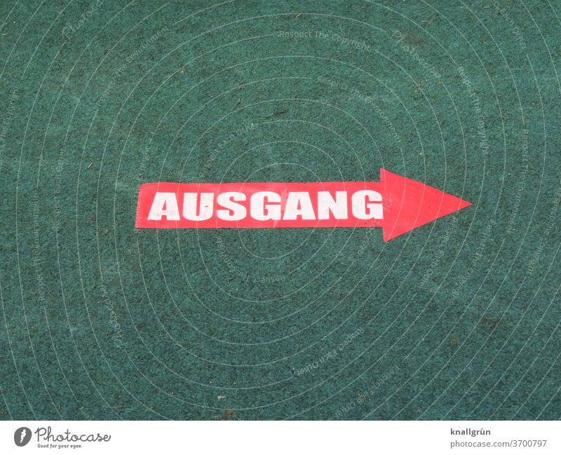 Red arrow with the word "AUSGANG" in white letters on a green carpet Way out Arrow Signs and labeling Signage Direction Clue Road marking Orientation Navigation