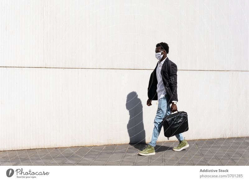 Confident ethnic businessman walking on street medical mask city epidemic coronavirus entrepreneur protect male black new normal african american barcelona