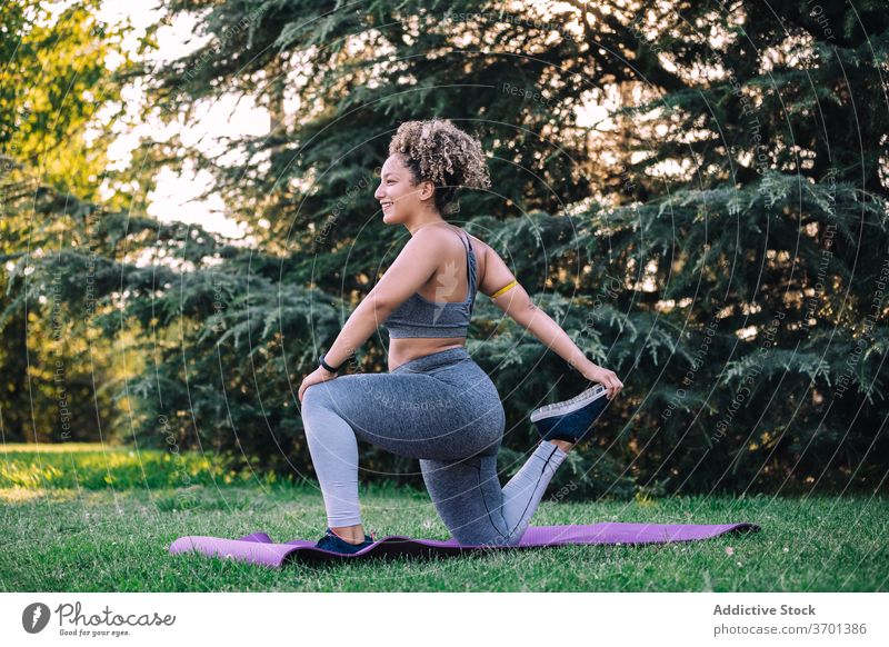 Fit woman stretching legs during training in park exercise lunge fitness sporty cheerful young workout healthy sportswear wellness female ethnic lifestyle