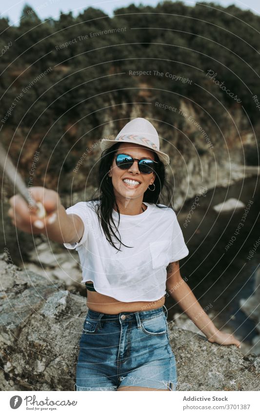 Smiling woman taking selfie while traveling traveler selfie stick hill mountain tourist take photo smile carefree female content adventure memory moment tourism