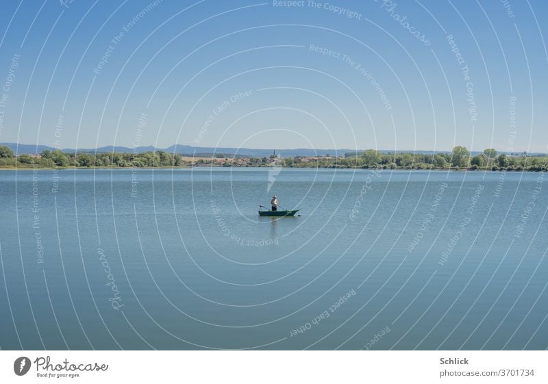 A single fisherman in his boat on a lake Lake Angler Village Church rural Blue Landscape Lonely silent Place Lorraine Channel Water Horizon tranquillity wide