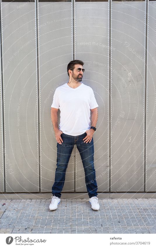 Bearded man in sunglasses leaning on metallic wall with hands on pocket while looking away 1 bearded standing carefree people person lifestyle copy space