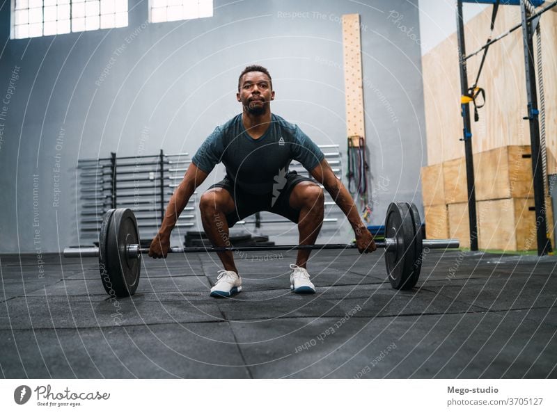 Crossfit athlete doing exercise with a barbell. man fitness workout muscles concentration crossfit training sportive concept crossfit gym black activity