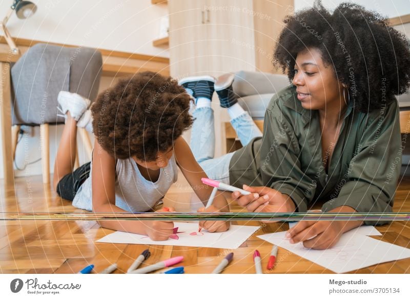 Mother and son drawing with colored pencils on floor. fun mother home together mom black people african american mixed race family kids leisure floor fun indoor