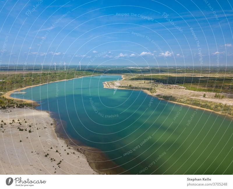 Wind wheels for green energy in the background of a torquiose colored lake. wind generator electric environmental politics electricity power windmill generation