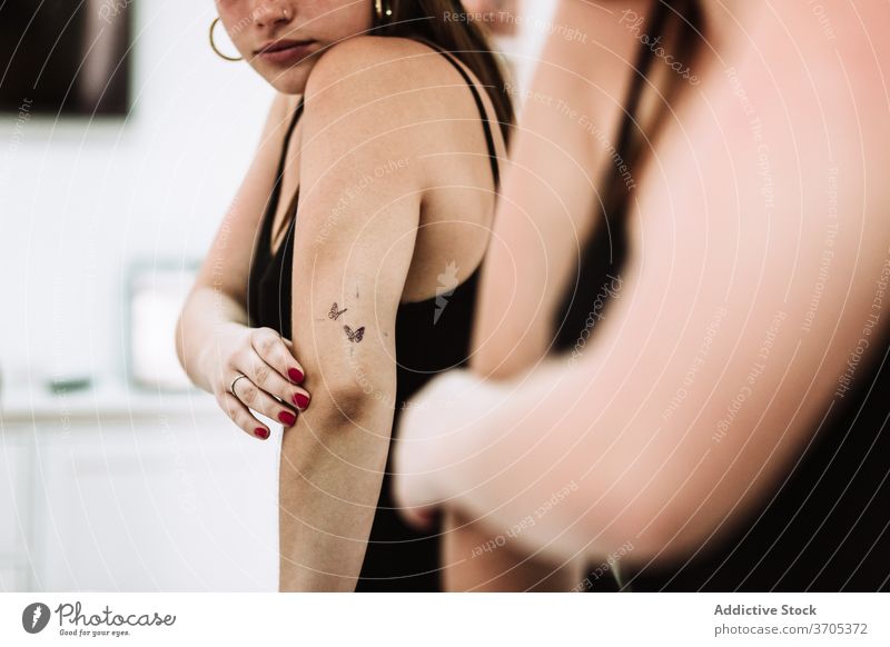 Happy woman with new tattoo looking at mirror arm examine satisfied happy salon client young female art culture reflection style customer fashion service design