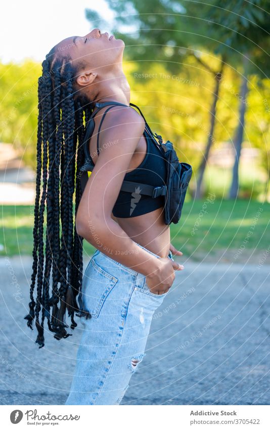 Sensual ethnic woman in trendy outfit standing in park style young braid fashion street style hipster african american urban black millennial female jeans