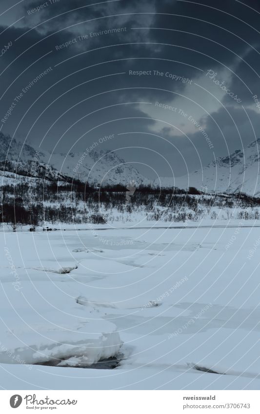 Frozen Vestpolltjonna bay. Lilandstinden-Geitgallien-Durmalsfjellet mounts background. Austvagoya island-Nordland fylke-Norway. 0102 frozen icy ice sheet snow