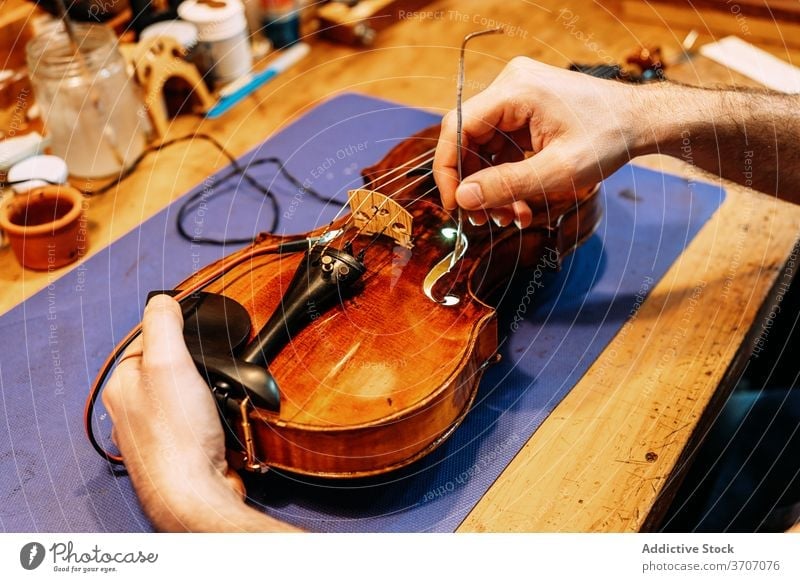 Anonymous luthier installing sound post to violin insert make instrument artisan craft tool hand work setting workshop equipment cello skill master maker
